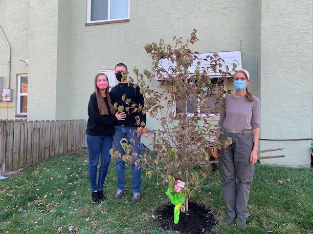 Cari poses with her mother's tree and her son Ben and daughter-in-law Hannah